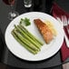 A Tuxton Alaska bright white wide rim china plate with salmon and asparagus.