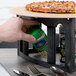 A person using a pepper shaker on a pizza on a HS Inc. Tower of Pizza Stand.