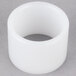 A white plastic bushing with a hole on a grey surface.
