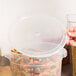 A person holding a Cambro translucent round plastic food storage container with pasta inside.