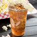 A Bare by Solo RPET disposable plastic cup filled with iced tea and a lemon wedge.