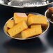 A bowl of food on a table with cornbread slices in a round hammered stainless steel bowl.
