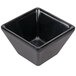 An American Metalcraft black melamine square sauce cup on a counter.