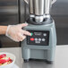 A person uses a Waring 1 Qt. Size Adapter in a commercial blender to blend a bowl of sliced apples.