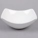 A white American Metalcraft square stoneware bowl with a curved edge on a white surface.