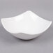 An American Metalcraft white stoneware bowl with a curved edge on a gray surface.
