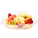 A Fineline clear plastic serving bowl filled with fruit on a white background.