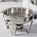 A Vollrath stainless steel water pan in a Maximillian steel chafer on a white table.