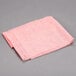 A folded pink Chicopee Quix Plus sanitizing towel on a gray surface.