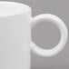 A close-up of an Arcoroc Daring white stack mug with a handle and a ring.