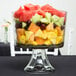 An Anchor Hocking glass trifle bowl filled with fruit salad on a table.