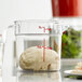 A Cambro clear plastic food storage container with a ball of dough inside.