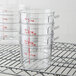 A wire rack holding three Cambro clear plastic food storage containers.