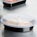 A Pactiv plastic container with food and a lid on a table.