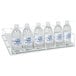 A white Beverage-Air Gravity Flo rack holding six bottles of water with blue labels.