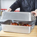A person holding a Vollrath aluminum double roaster pan with food inside.