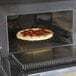 A pepperoni and bacon pizza cooking in a Merrychef eikon e5-1530 high-speed countertop oven.