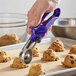 A close-up of a hand using a purple Zeroll EZ Squeeze handle to scoop ice cream.