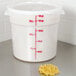 A white Cambro round food storage container filled with noodles next to a white measuring cup with red lettering.