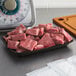A black foam CKF meat tray on a counter with raw meat on it.