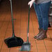 A woman using a Rubbermaid commercial broom with a black pole.