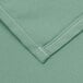 A close up of a seafoam green fabric with white stitching.