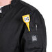 A man wearing a black Chef Revival chef coat with a yellow pen and thermometer in the pocket.