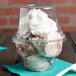 A clear Fabri-Kal PET sundae cup filled with ice cream and whipped cream.