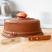 A chocolate cake with a strawberry on top with an Ateco offset spatula on a wooden table.