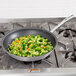 A Vollrath Wear-Ever non-stick fry pan filled with broccoli and carrots on a stove.