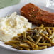 A plate of mashed potatoes and green beans on a table.