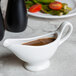 An American Metalcraft white porcelain gravy boat with brown sauce in it.