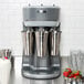 A Hamilton Beach triple spindle drink mixer with silver cups on the counter.