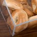 A clear container with bagels in a Cal-Mil bakery display case.