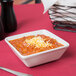 A Tuxton TuxTrendz bright white square china bowl filled with chili and cheese on a table.
