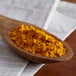 A wooden spoon filled with Regal Ground Turmeric powder on a white cloth.