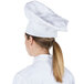 A woman wearing a white Chef Revival chef hat.