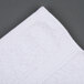An Oxford Gold white cotton-polyester hand towel on a gray surface.