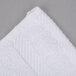 A close up of a white Oxford Signature wash cloth with a square edge.