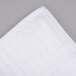 A close-up of a white Oxford Signature bath towel on a gray surface.