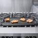 A Lodge cast iron griddle with grilling chicken on a stove.