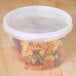 A translucent plastic round deli container filled with multicolored spiral pasta.