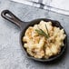 A Lodge mini cast iron skillet of macaroni and cheese with a rosemary sprig.