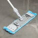 A blue Unger SmartColor MicroMop dry mop pad attached to a mop handle.