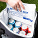 A hand putting a Polar Tech Re-Freez-R-Brix foam freeze pack in a cooler filled with blue soda cans.