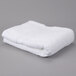 A white folded Oxford Miasma bath towel on a gray surface.