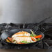 A Lodge carbon steel fry pan with fish and vegetables cooking in it.