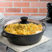 A Lodge cast iron pan with a tempered glass lid covering macaroni and cheese.