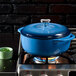 A Caribbean blue Lodge enameled cast iron Dutch oven with a lid on a stove.