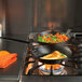 Lodge carbon steel fry pan with eggs and vegetables cooking on a stove.